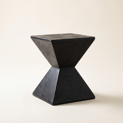 Kaya hourglass side table in black solid wood on a plain off-white background