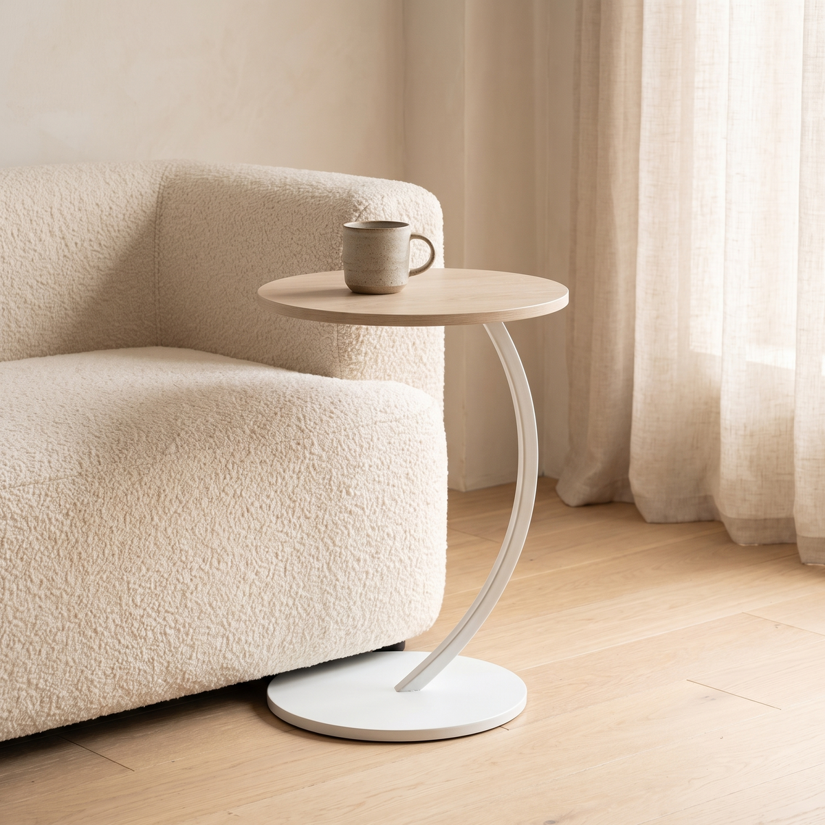 Orla Curve Side Table in light oak effect with white frame beside a sofa