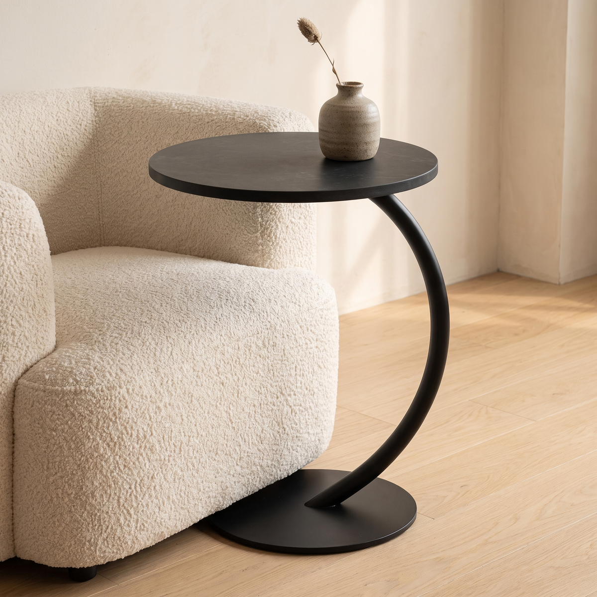Orla Curve Side Table in black stone effect with black frame beside an armchair