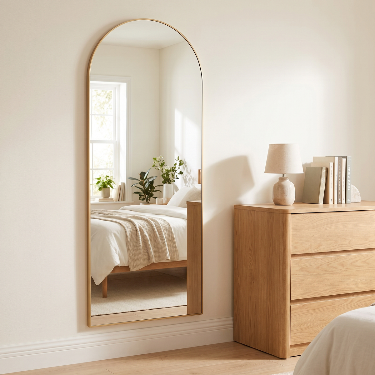 Aria gold arched mirror mounted on a bedroom wall