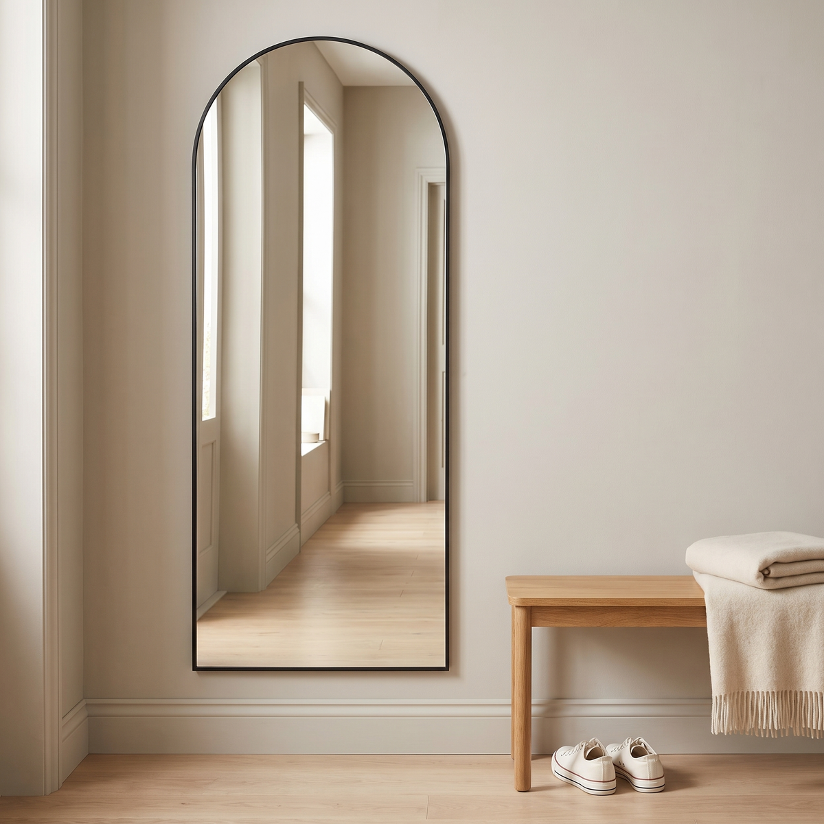 Aria black arched mirror mounted on a hallway wall
